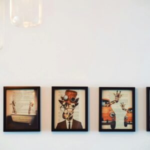 A modern interior display of four framed giraffe-themed artworks, enhanced by warm lighting.